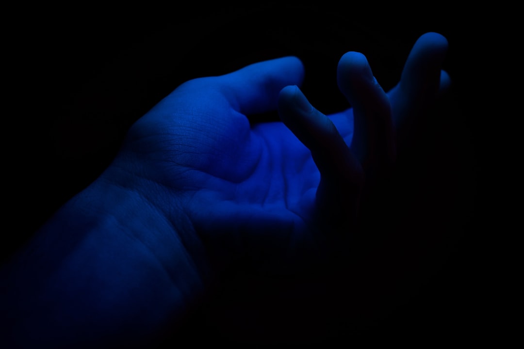 Close-up of a human hand touching a glowing, futuristic digital screen, symbolizing the collaboration between human creati...