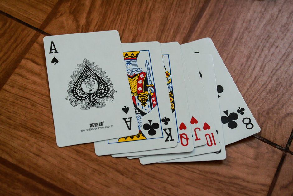 A house of cards captured mid-collapse on a wooden table, illustrating the fragile and unstable nature of a cheap SEO strategy that lacks a solid foundation.