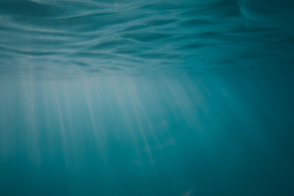 The tip of an iceberg visible above the water with the massive, hidden bulk of ice visible beneath the deep blue sea, representing the hidden costs and unseen damage of cheap SEO services.