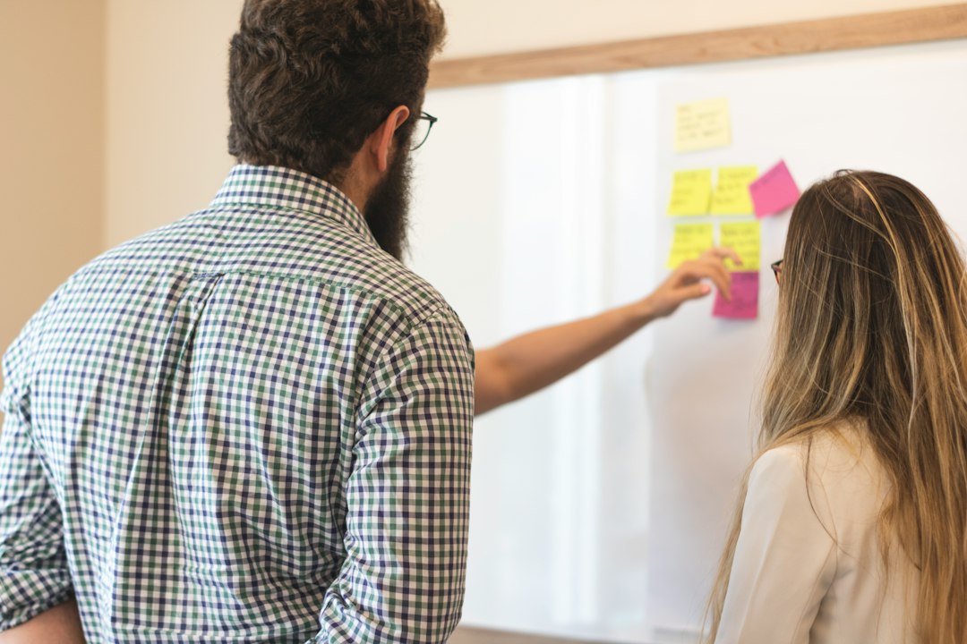 A diverse team of professionals collaborating on a strategic plan by writing on a glass wall in a bright, modern office, illustrating a modern, integrated approach.