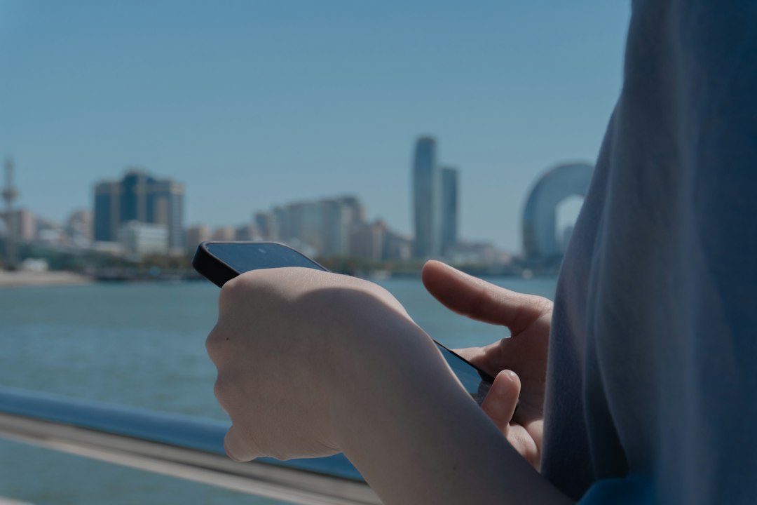 A professionally dressed woman stands in a modern city, holding a smartphone that displays a map application, representing local SEO and digital navigation in real estate.